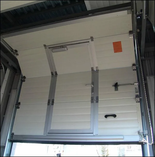 Industrial sectional garage door with pedestrian door insert